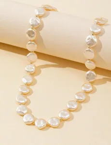 Dettaglio ravvicinato di una collana minimalista di perle barocche piatte.