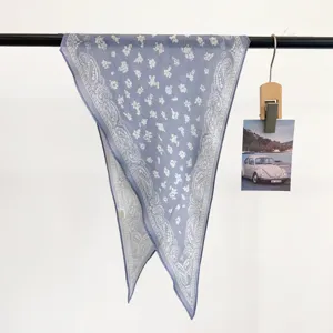 Close-up detail of a vintage blue cotton bandana with white paisley and floral patterns