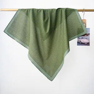 Green retro polka dot cotton square scarf hanging on a wooden rod