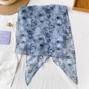Detailansicht eines hellblauen Chiffon-Schals mit Blumenmuster als elegantes Haarband
