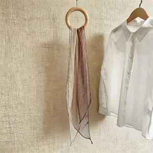 Detailansicht eines weichen braun-weiß gestreiften Chiffon-Schals an einem Holzring