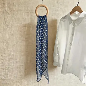 Detailansicht eines eleganten marineblauen Chiffonschals mit weißen Punkten und Hemd