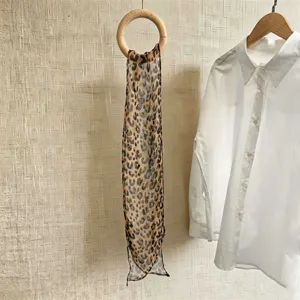 Detaillierte Ansicht eines eleganten Chiffonschals mit Leopardenmuster an einem Holzring