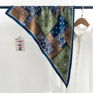 Vue détaillée d'un foulard en soie vintage bleu et vert à motif paisley pour le cou.