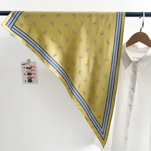 Gros plan détaillé du foulard triangle en soie jaune moutarde avec rayures bleues