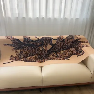 Detail of luxury leopard print shawl draped elegantly on a cream leather sofa