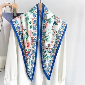 Vista dettagliata di un foulard in seta a fiori con bordo blu drappeggiato su camicia bianca