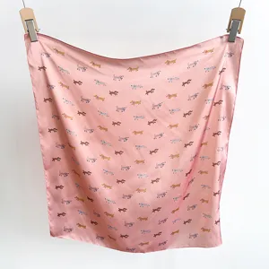 Detail eines rosa quadratischen Seidenschals mit Cartoon-Hundemuster, an Clips hängend.