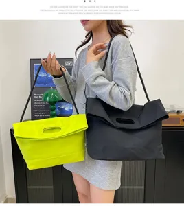Large nylon tote bag in neon yellow and black colors, worn by a lifestyle model.
