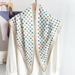 Dettaglio di foulard a triangolo in seta bianca con stampe di cavalli colorati.