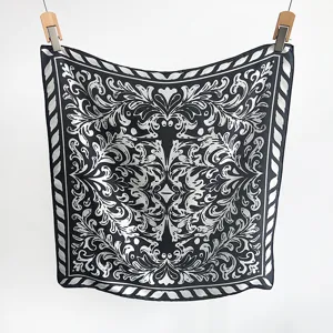 Detailed view of the symmetrical baroque pattern on a black and white faux silk scarf.