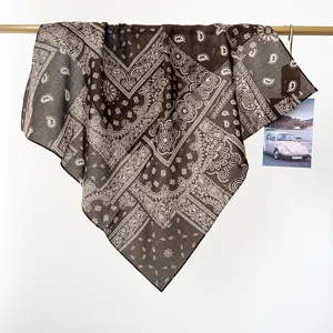 Primer plano de una bandana paisley de algodón marrón colgada de una barra dorada