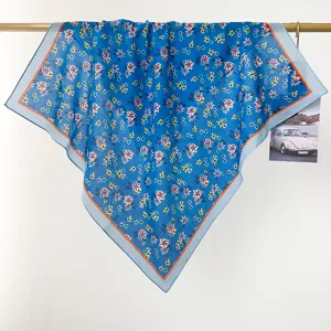 Dettaglio di un foulard quadrato in cotone a fiori blu appeso a un’asta di legno chiaro