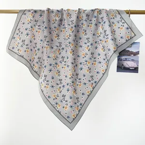 Vista dettagliata di un foulard quadrato in cotone grigio con stampa floreale su asta