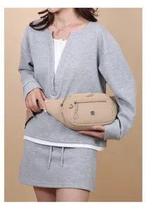 Close-up of a lightweight khaki nylon waist bag worn by a model in a casual grey outfit.