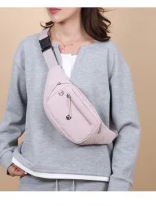 Close-up of a pink lightweight women's crossbody chest bag worn with a grey sweatshirt