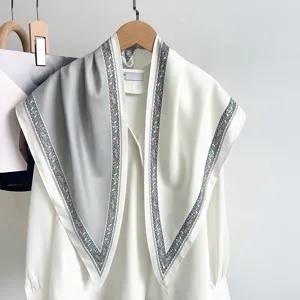 Vue détaillée d'un foulard triangle bicolore gris et blanc sur un chemisier.