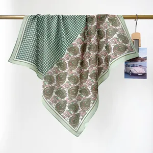 Detailweergave van een groene katoenen sjaal met pied-de-poule en paisley motief aan gouden bar.