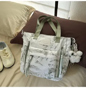 Detailed view of the landscape pattern and plush bunny charm on a fashion student tote bag