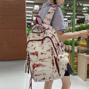 Detailed view of white backpack with red landscape print and fluffy bear charm
