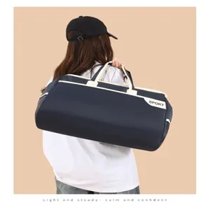 A detailed view showing the large navy blue sports travel duffel bag carried by a model