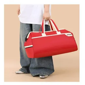 Close-up detail of a large red travel duffel bag held by hand for sports and fitness use