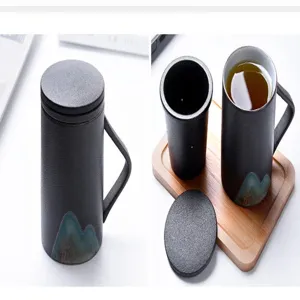 Dettaglio tazza da tè in ceramica nera opaca con infusore e vassoio in legno naturale