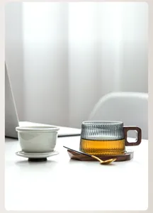 Elegante gerippte Glasteetasse mit Holzgriff und passendem Untersetzer im Büroambiente