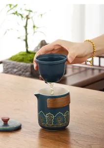 Détail d'un service à thé en céramique bleue avec poignée en bois et motifs de lotus dorés.