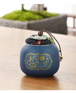 Vue détaillée d'une boîte à thé en céramique bleue avec couvercle en tissu fleuri