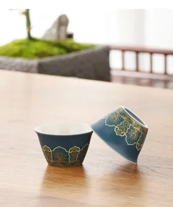 Gros plan de tasses à thé en céramique avec motifs floraux bleus et dorés sur bois