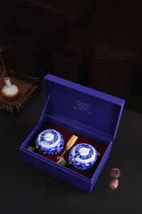 Macro detail of elegant blue and white porcelain tea canisters set in a luxury purple gift box.