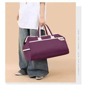 Large purple travel duffel bag for gym and weekend trips carried by stylish model