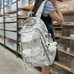 Stylish white backpack featuring green landscape print and a cute plush bunny keychain accessory
