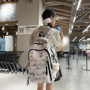 Detail view of a stylish ink-wash print school backpack worn by a girl in a mall setting.
