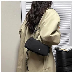 Rückansicht einer schwarzen Nylon-Outdoor-Umhängetasche über einem beigen Trenchcoat