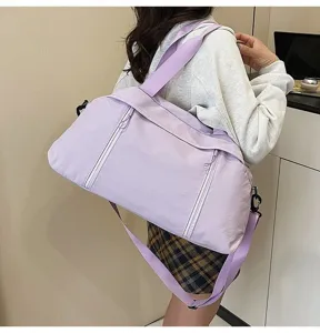 Close-up of a purple sports gym bag with an adjustable strap worn by a female model.