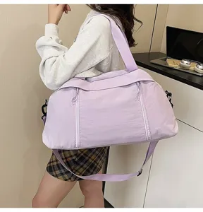 Large lavender sports gym bag worn over the shoulder by a person in a modern interior.
