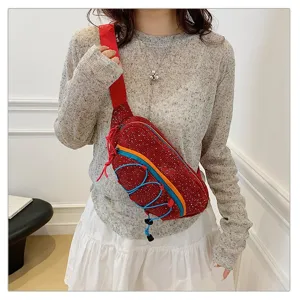 Detailed view of women's red corduroy crossbody chest bag with colorful bungee cords