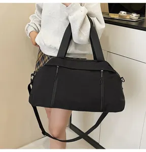 Close-up of black lightweight travel duffel bag carried by model in modern room