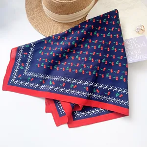 Detail view of navy blue cotton square scarf featuring cute cherry print and red border