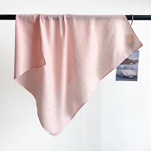 Detail of pink polka dot silk scarf draped on a bar showing breathable texture
