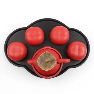 Red persimmon-shaped ceramic tea set with one teapot, four cups, and tray