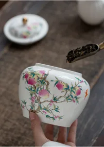 Détail de boîte à thé en céramique blanche avec motif de pêchers pour thé en vrac.