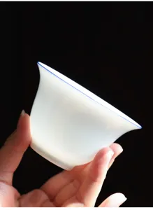 Dettaglio di una tazzina da tè in porcellana bianca Dehua traslucida con bordo blu fine.