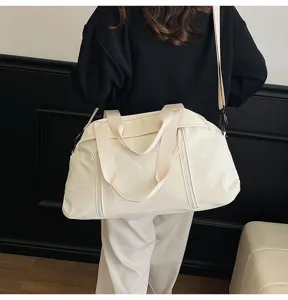 Cream-colored large capacity sports gym bag with shoulder strap worn by person