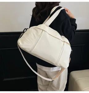 Model wearing a large white travel duffle bag, detail view showing strap and back profile.