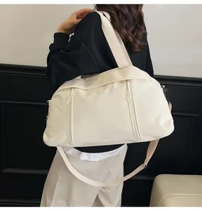 Stylish cream-colored yoga gym bag for sports and travel carried over shoulder by a model.