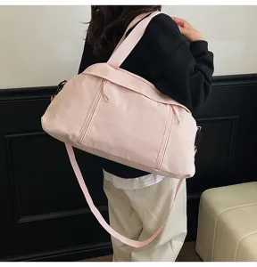 Pink lightweight travel duffel bag carried by model for gym or yoga session