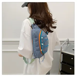Back view of a blue corduroy chest bag with orange accents and bungee cord detail